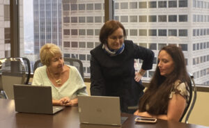 Diana Haskell, Kate Feuerberg, and Kim Beck working together in an office